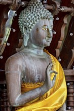Close-up of a Buddha statue in bronze with a bright yellow cloth, The Seema Malaka temple with the