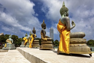 Buddha statues on the water with yellow robes against an urban backdrop, The Seema Malaka Temple