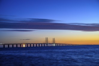 Modern Øresund bridge across the sea at sunset with colorful sky illuminated by a colorful sunset,