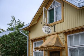 Street scene in the old town of Naantali, yellow wooden house with a rustic charm and a sign