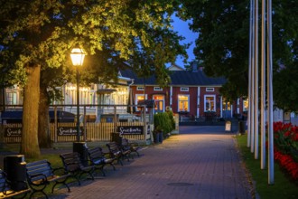 Illuminated alley in the old town of Naantali with benches and trees at dusk, cozy atmosphere,
