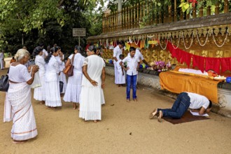 People in white celebrate a ceremony with prayers and offerings in front of a decorated altar, The