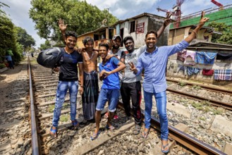 Group of men partying on railroad tracks, showing a gesture and cheerful atmosphere, friends on the