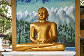 Golden Buddha statue in front of a painted wall with landscape motif, The Seema Malaka temple with