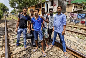 Group of men pose on railroad tracks in an urban setting, showing friendship and smiles, friends on