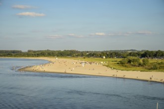 A sunny beach on Priwall near Rosenhagen with people on the shore, surrounded by green countryside