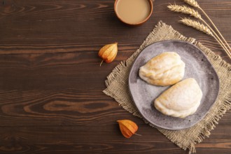 Glazed Pies with Cowberry jam on brown wooden background and linen textile, cup of coffee, top