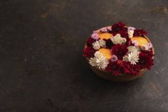 Wooden bowl with carrot slices and red Chrysanthemum flowers, Astrantia flowers, flower salad on