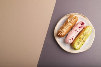 Glazed Eclairs on gray and brown pastel paper background, top view, flat lay, copy space