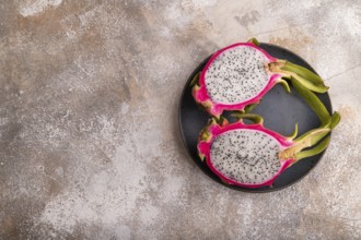 Ripe Pitaya on blue plate on brown concrete background, top view, flat lay, copy space, minimalism