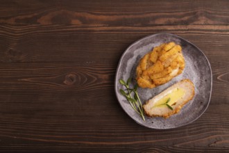 Chicken Schnitzel on gray plate with microgreen on brown wooden background. top view, flat lay,