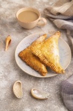 Triangles Pie, Puff Pastry, Samsa with cherry jam on brown concrete background and linen textile,