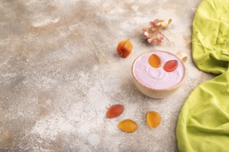 Purple Yogurt, with jelly candy on brown concrete background and green textile, side view, copy