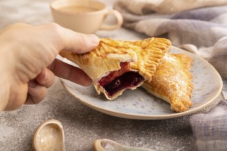 Triangles Pie, Puff Pastry, Samsa with cherry jam on brown concrete background and linen textile