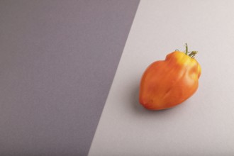 Red Heart Shape tomato on black and gray pastel paper background. Side view, copy space. healthy
