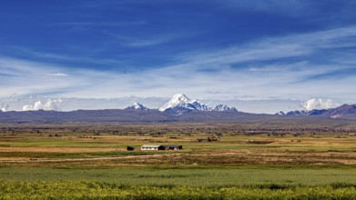 Green fields in the foreground with snow-covered mountain in the distance, The landscape of the