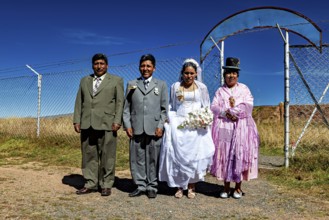 Wedding couple and companions in traditional clothes in front of fence and blue sky, traditional