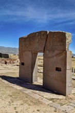 Ancient stone gate in open landscape with mountains and clear sky, The archaeological site with the