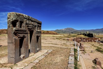 Ancient stone structures in a vast, mountainous landscape under clear blue skies, the