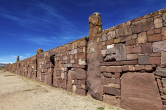 Ancient stone wall stretching along a narrow path under blue sky, the archaeological site with the