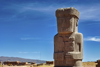 Large ancient stone statue under clear sky, showing detailed engravings, the archaeological site