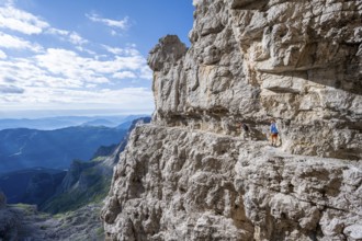Two mountaineers on an exposed rock band in the secured via ferrata Bocciere Centrale, Brenta