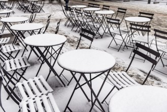 Winter in Stuttgart. Outdoor dining chairs and tables are covered with snow. Geometric structures.