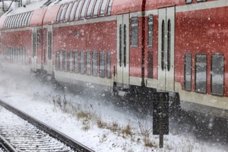 RegionalExpress RE on the road through a winter landscape in snowfall. A train on the line in the