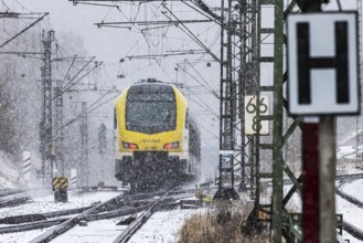 Regional train from Arverio on its way through a winter landscape in snowfall. The railcar train is