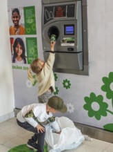 Two children, 5 and 7 years old, earn pocket money by recycling cans in a recycling machine in