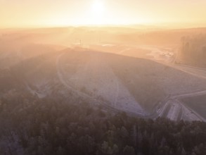 A large hill surrounded by forest, in foggy sunrise, old deposit, construction site for PV open