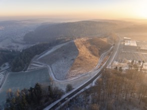 Small hill surrounded by wooded landscape in the light of the evening sun, old deposit,