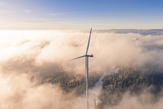 Wind turbine juts out of cloud cover, surrounded by foggy landscape at sunset, Bad Wildbad, Calw