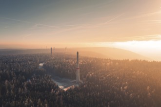 Dawn over a foggy forest with several wind turbine towers rising from the trees, Windkraft Bau,