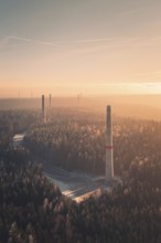 Wind turbine towers tower above a forest at sunset, soft pastel colors and fog create a quiet