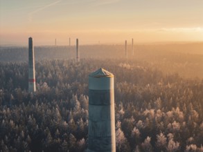 In the distance, smoke-free wind turbine towers stand over thick fog, the winter forest and an