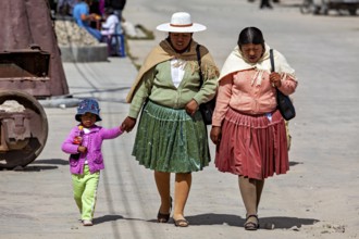 Two woman and a child in colorful, traditional clothing walking hand in hand on the street, people
