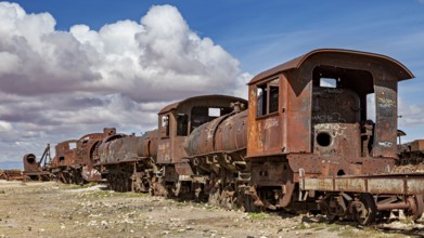 Several rusted locomotives on a dry surface under a cloudy sky, old rusty locomotives at the train