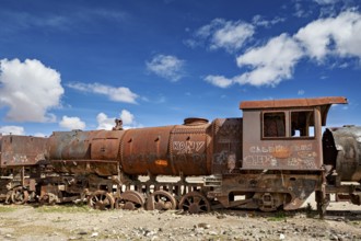 Abandoned and rusty locomotive with graffiti under a dramatically cloudy sky, old rusty locomotives