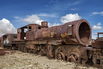 Rustic, graffiti-decorated locomotive in an open, cloudy landscape, old rusty locomotives at the