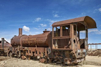 Rusted steam locomotive in an abandoned area under a blue sky, old rusty locomotives at the train