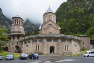 Historic monastery building surrounded by mountains and clouds in a peaceful atmosphere, Dariali