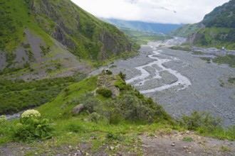 View of a green valley with a riverbed and surrounding mountains under cloudy sky, Tergi River,