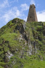 Historic ruin of a tower on a green rock face under a blue sky, Zion Tower, Sioni, Georgian