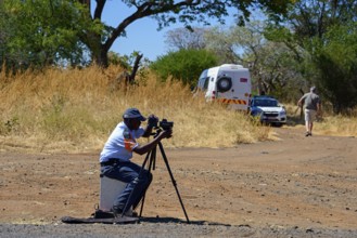 A policeman controls traffic with a camera on a tripod on the side of the road, man must pay fine
