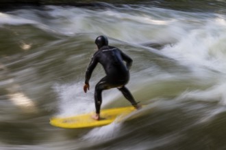 Surfers standing on Eisbach wave in the English Garden Munich, Upper Bavaria, Germany
