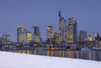 The towers of the Frankfurt banking skyline rise behind the snow-covered banks of the Main,