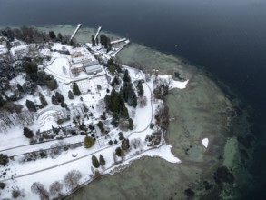 The wintry and snowy Mainau island in Lake Constance with the pier and the baroque Mainau Castle,