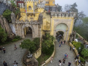 Tourists visiting the palace Palácio Nacional da Pena, foggy day, Sintra, Portugal