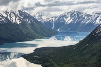 View of snowy mountains in spring and turquoise Kenai Lake with reflection, Slaughter Ridge Trail,